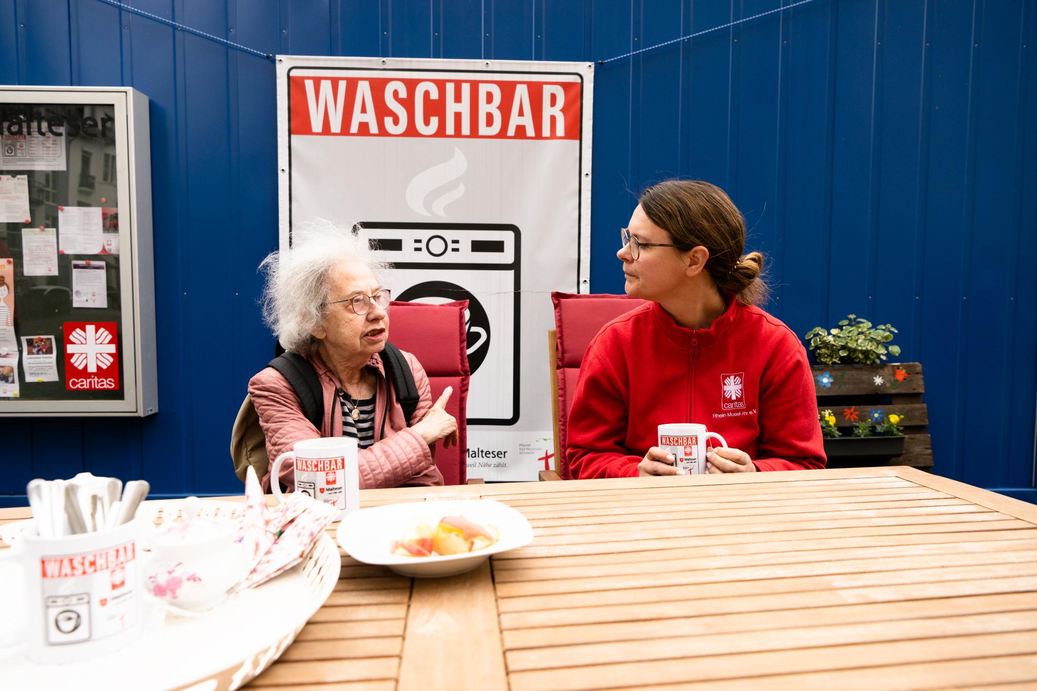 Eine Mitarbeiterin der Caritas hört einer Flut-Betroffenen in der Waschbar zu.