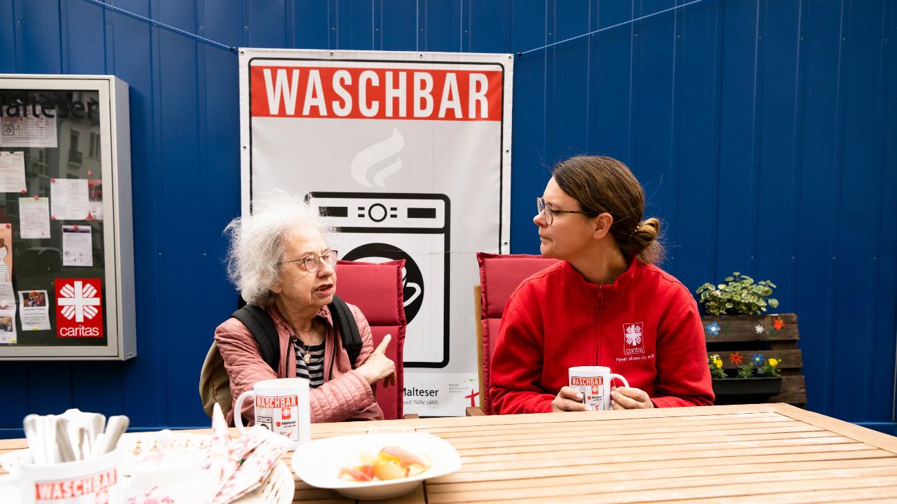 Eine Mitarbeiterin der Caritas hört einer Flut-Betroffenen in der Waschbar zu.