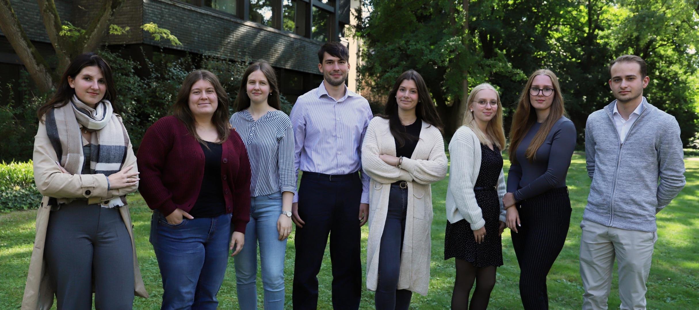 mehrere junge Menschen vor eine großen grünen Baum