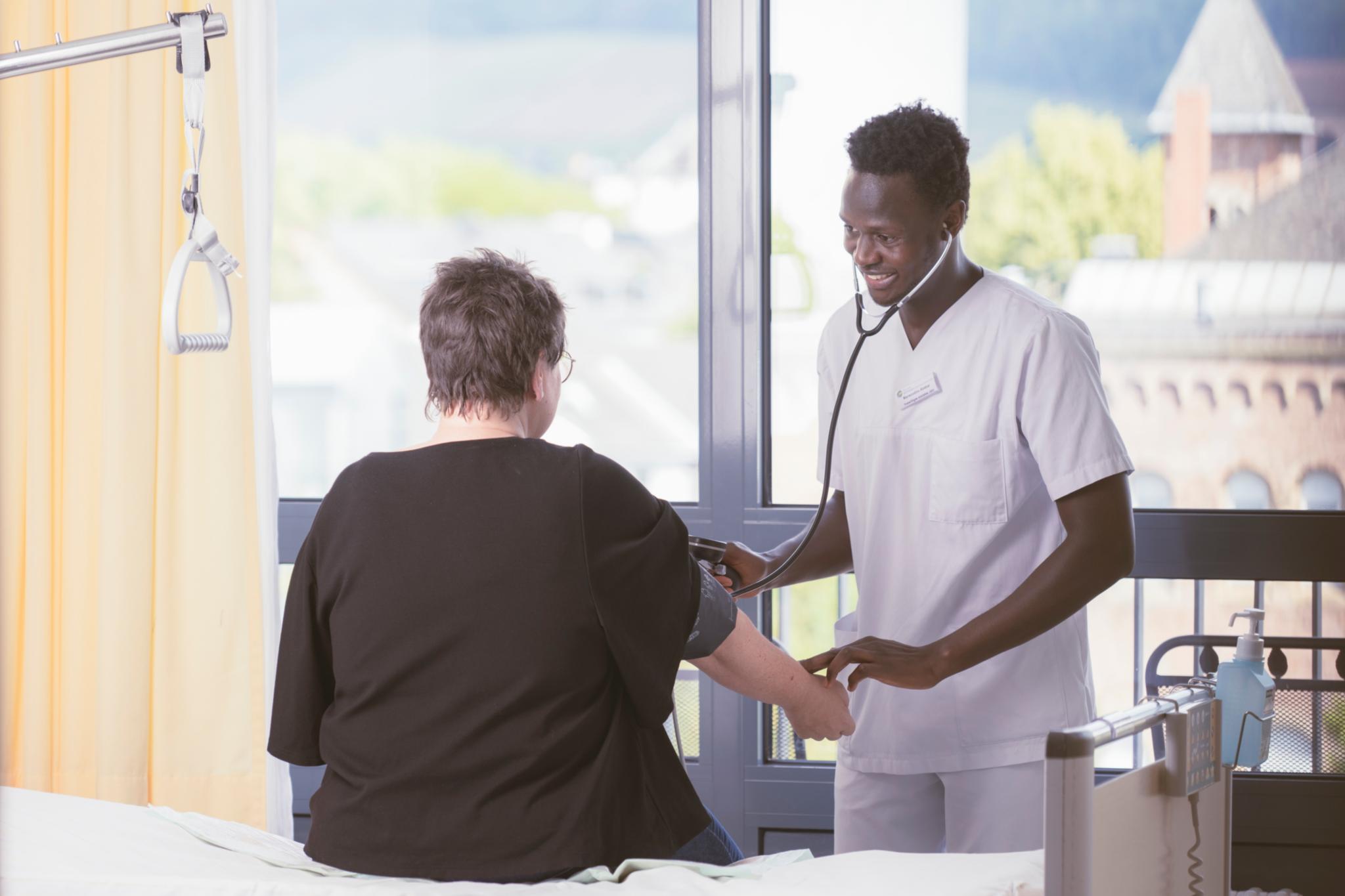 ein Junger Mann misst einer Frau den Blutdruck