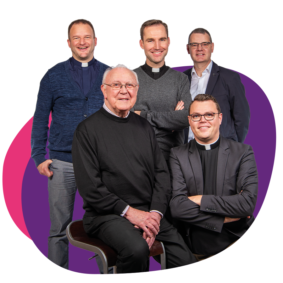 5 Priester unterschiedlichen Alters in Zivilkleidung bilden eine Gruppe und schauen lächelnd in die Kamera.