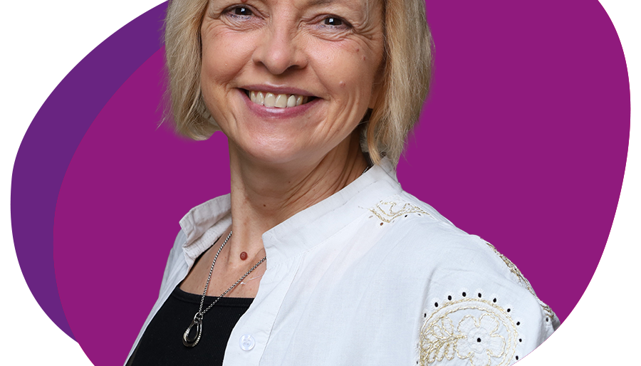 Freundlich lachende Frau mit kinnlangem, blondem Haar schaut in die Kamera.