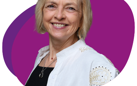 Freundlich lachende Frau mit kinnlangem, blondem Haar schaut in die Kamera.