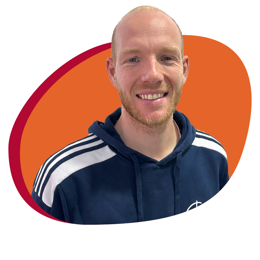 Junger Mann mit Trainingespulli lächelt freundlich in die Kamera.