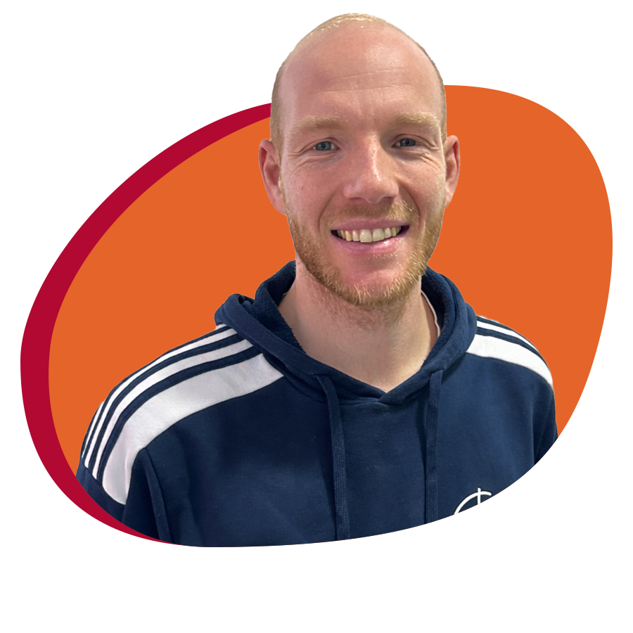 Junger Mann mit Trainingespulli lächelt freundlich in die Kamera.