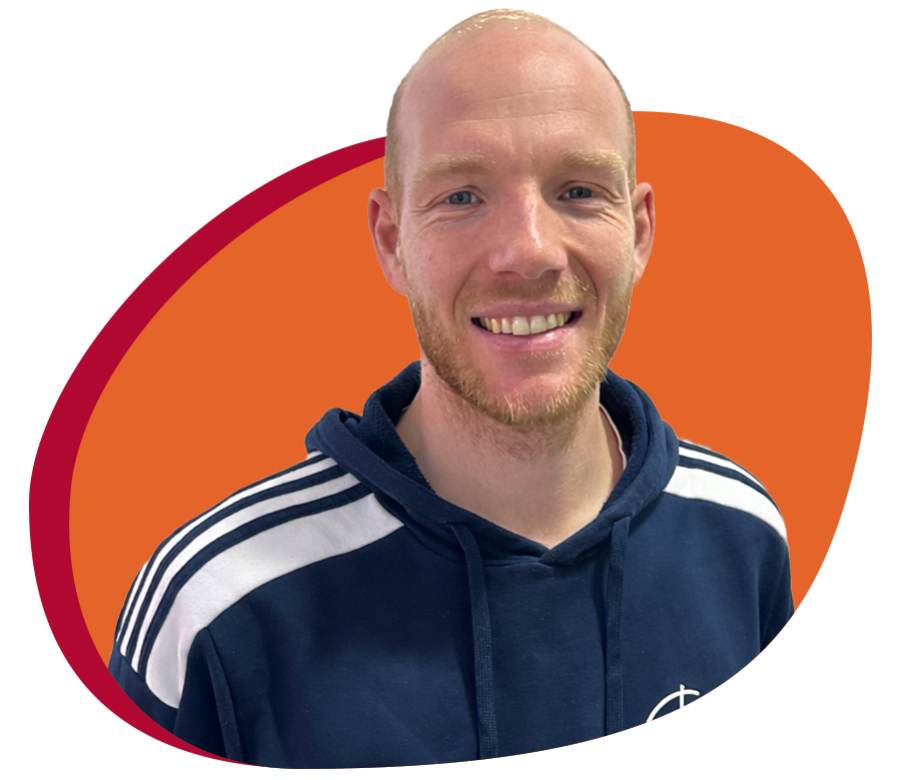 Junger Mann mit Trainingespulli lächelt freundlich in die Kamera.