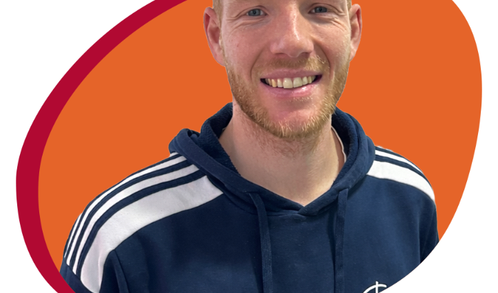 Junger Mann mit Trainingespulli lächelt freundlich in die Kamera.