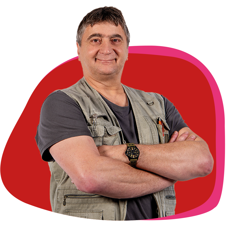 Älterer Herr verschränkt freundlich die Arme vor der Brust und lächelt in die Kamera.