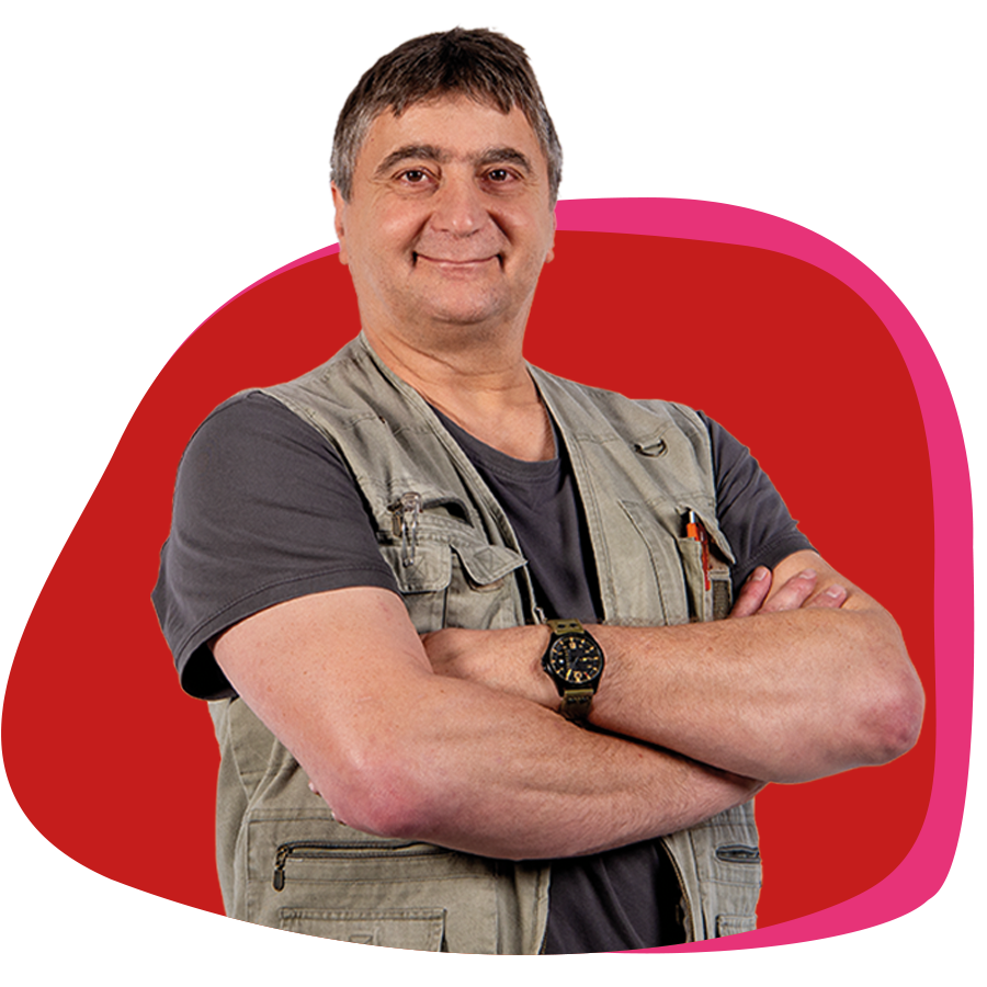 Älterer Herr verschränkt freundlich die Arme vor der Brust und lächelt in die Kamera.