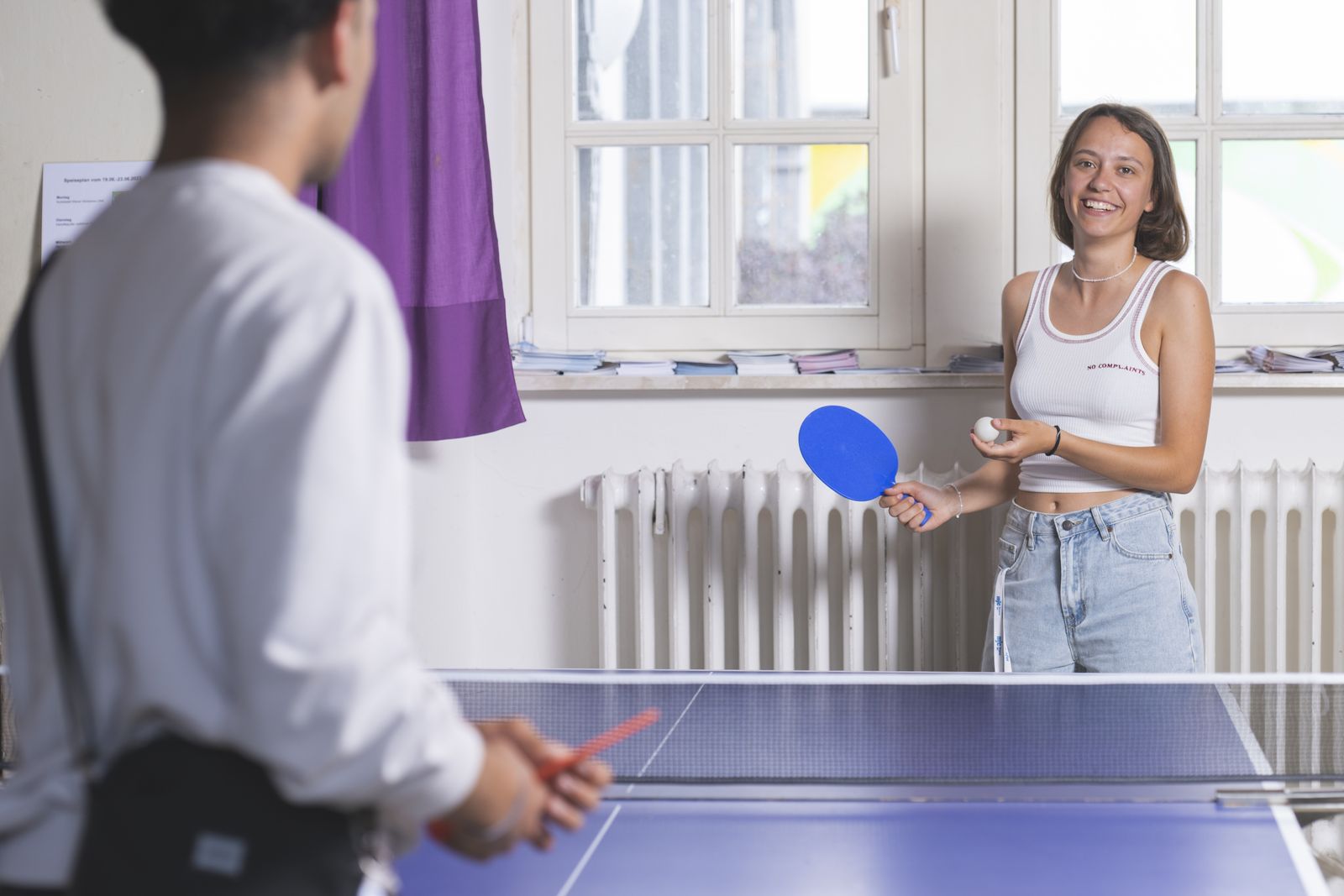 Eine Freiwillige spielt Tischtennis mit einem Jugendlichen.
