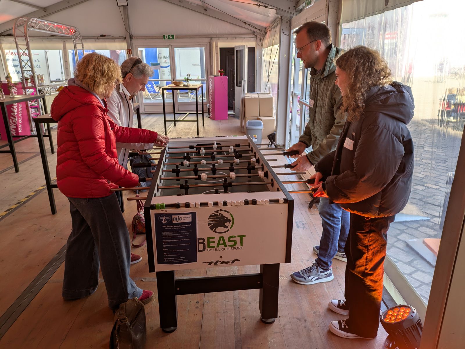 4 Leute spielen im Meet & Greet Zelt Tischfußball