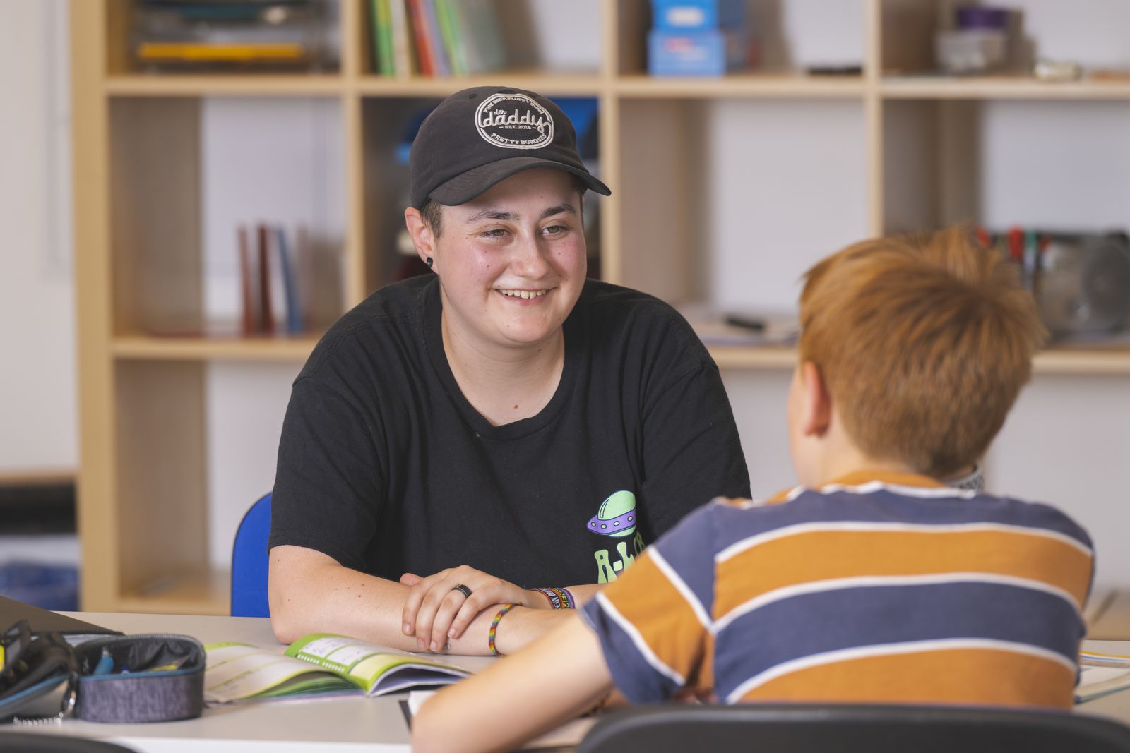 Junge Frau unterhält sich mit einem Jungen an einem Tisch.