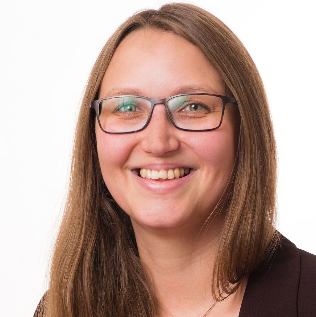 Junge Frau mit Brille lacht freundlich in die Kamera