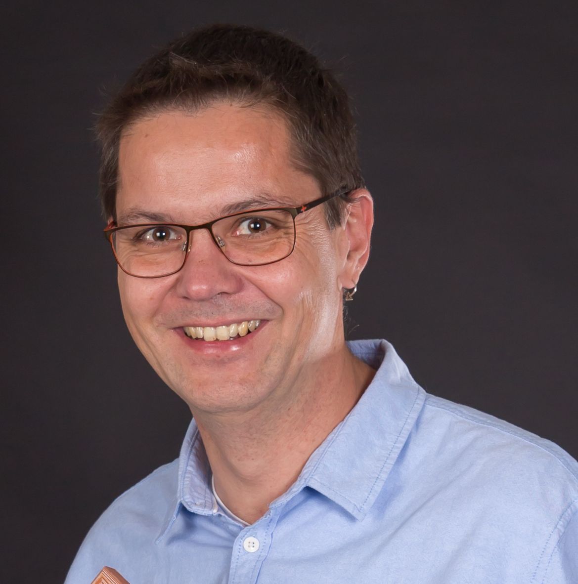 Mann mit Brille lächelt freundlich in die Kamera